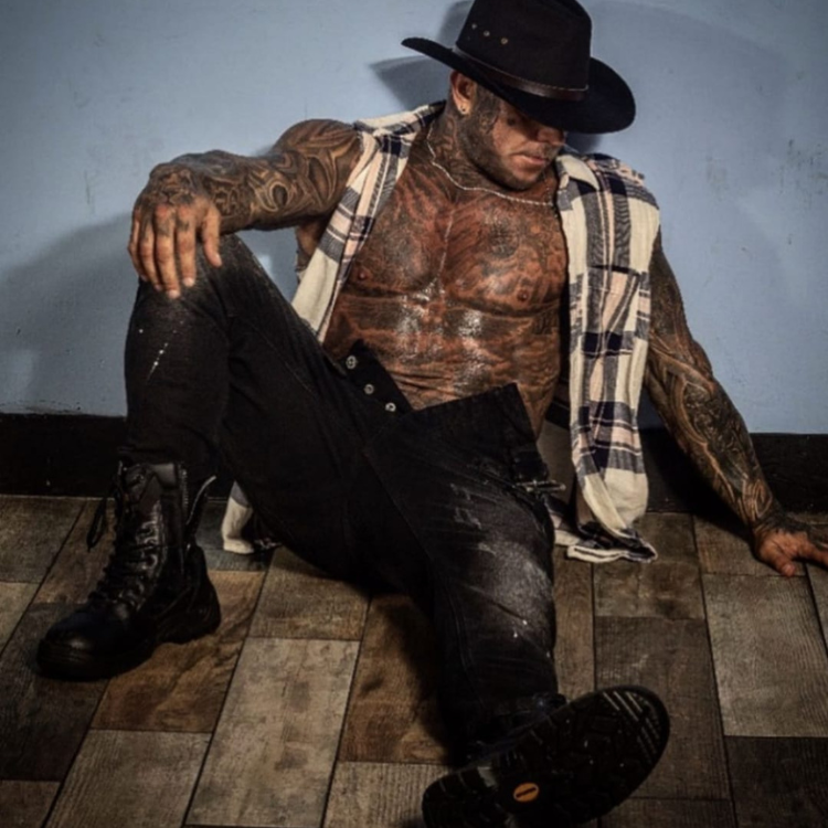 A male stripper in Surrey wearing jeans and a cowboy hat.
