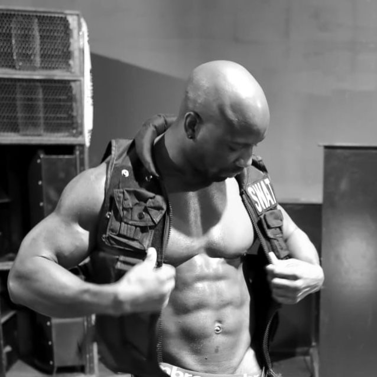 Male stripper in Charing wearing a black policeman sleeveless jacket, ready for a performance. Male Strippers in Charing