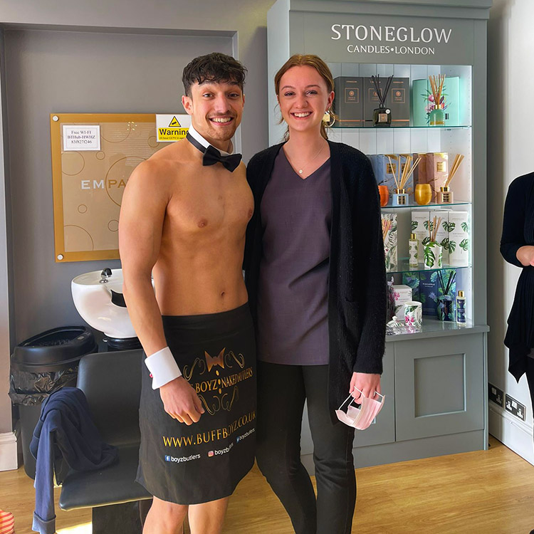 A naked butler with a bright smile standing next to an attendant at a corporate event.